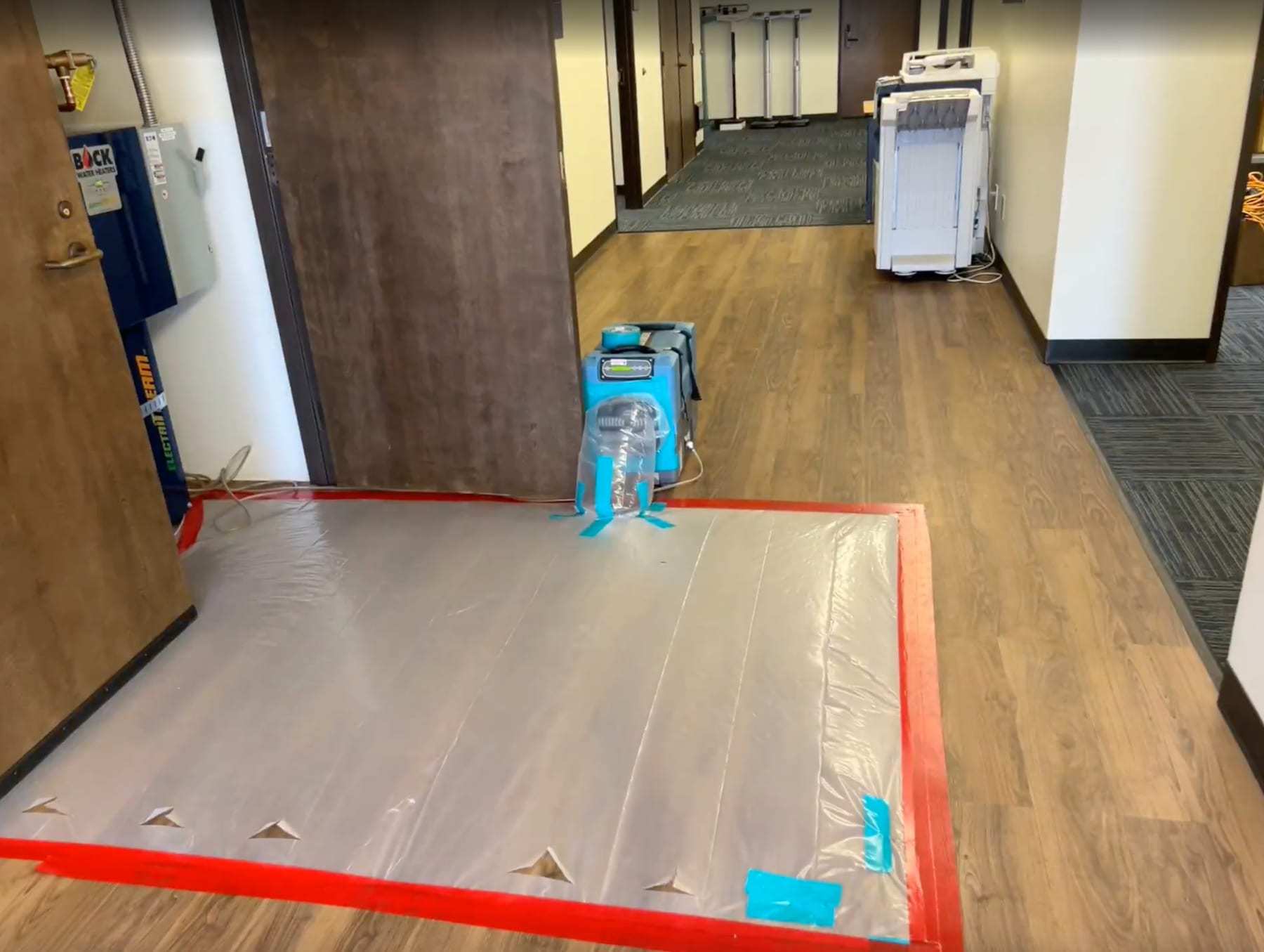 Hallway floor drying under plastic with a dehumidifier